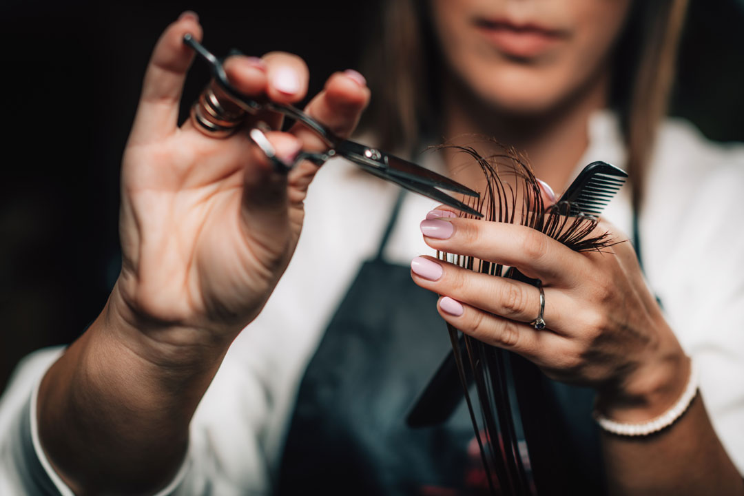 An uplclose image of a customer recieving trims from a professional hair stylist.