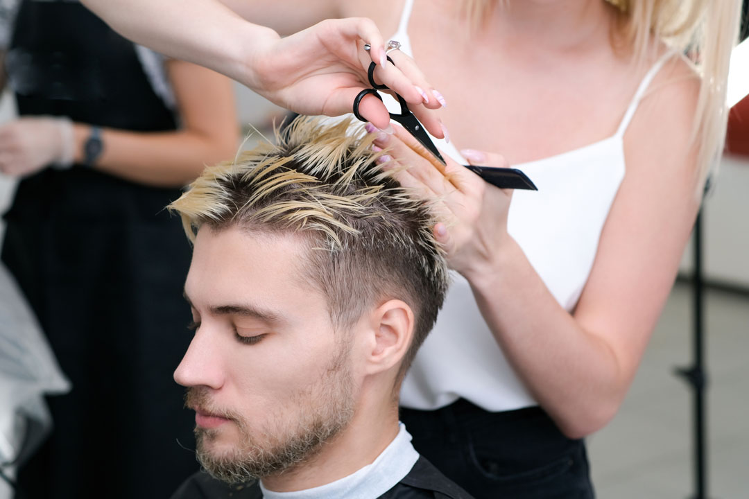 A man getting a haircut from a professional stylist - discover your potential with Cutting Crew Hair Salon in Oswego, NY.