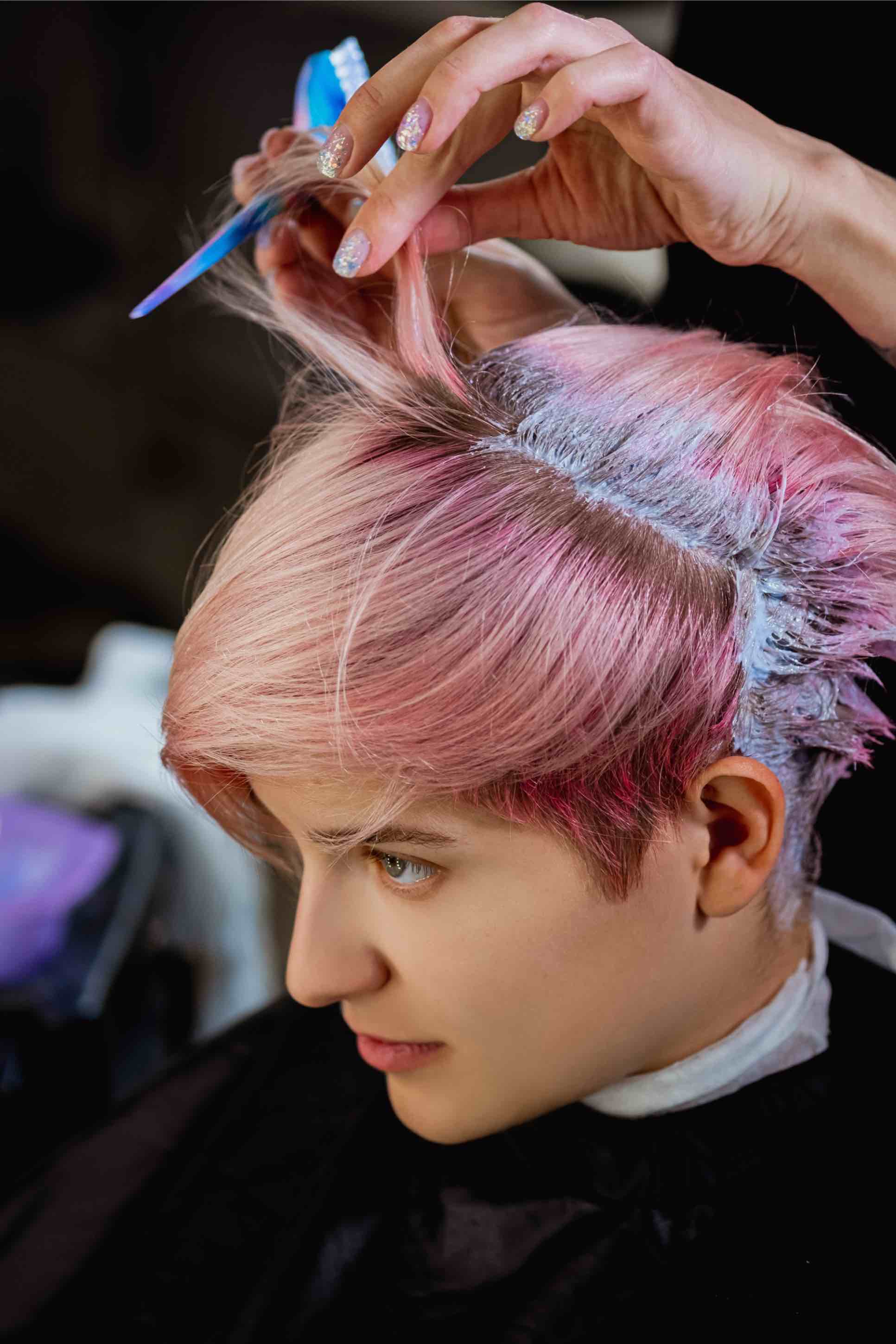 This woman with a pink pixie cut enjoys a low-maintenance cut with Cutting Crew Hair Salon.